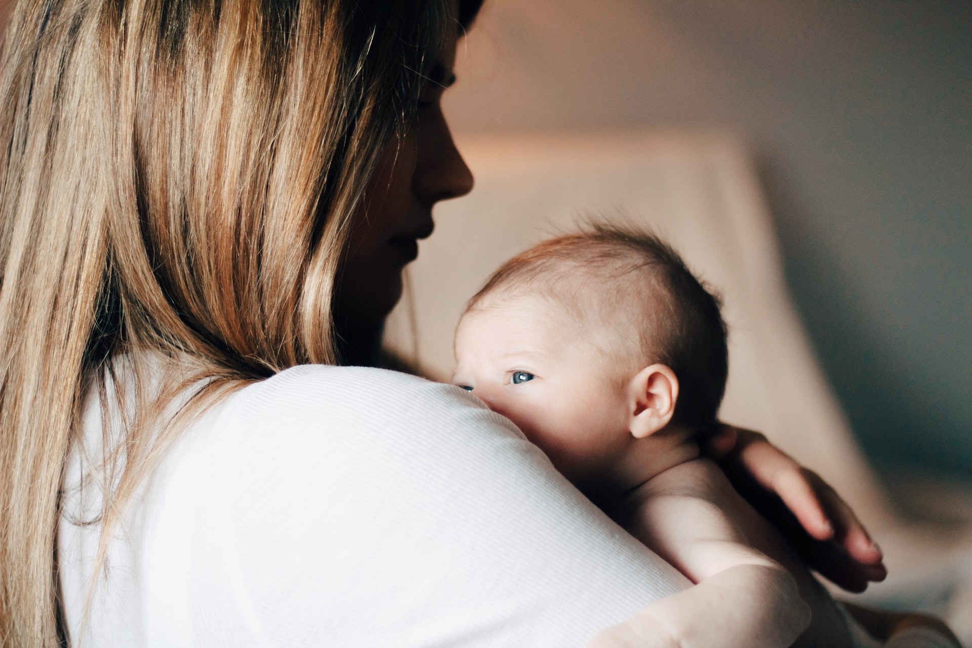 A mother comforting a baby on her shoulder