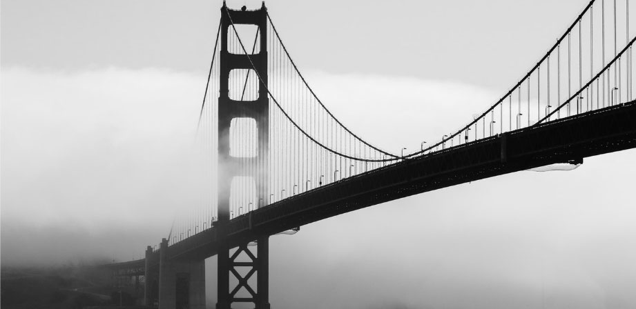 Black and white picture of Golden Gate Bridge partially covered in fog