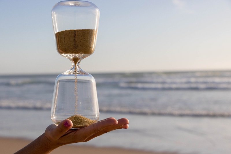 hourglass in hand at the ocean