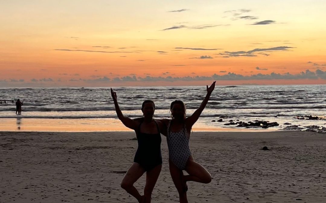 two people in yoga pose at sunset beach