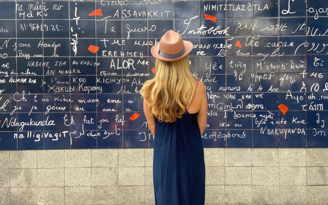 woman in standing in front of wall with love in different languages